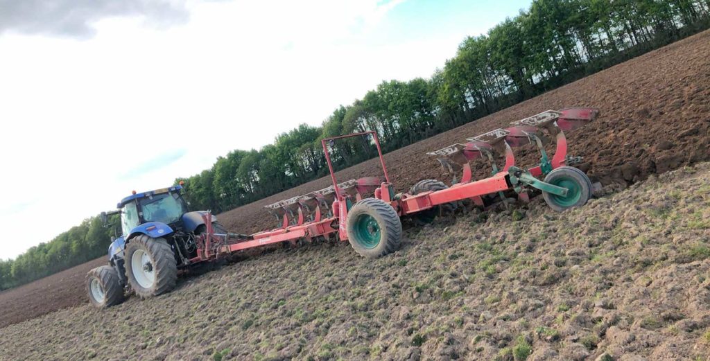 Charrue semi portée 8 corps KVERNELAND tractée par tracteur NEW HOLLAND T7050